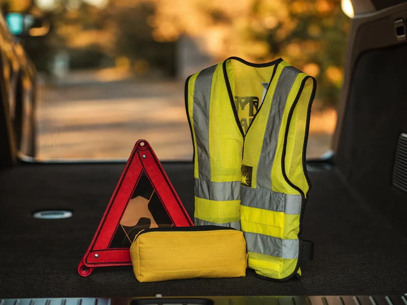 Notfallausrüstung mit Warndreieck, Warnweste und Verbandtasche im geöffneten Kofferraum
